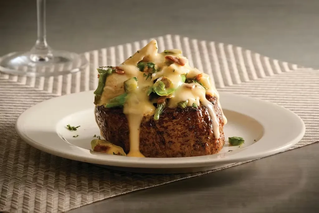 Thick steak with creamy sauce, green vegetables, bacon bits, dripping.