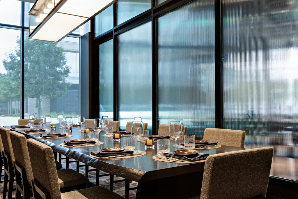 Long dining table in a modern restaurant with ribbed glass panels.