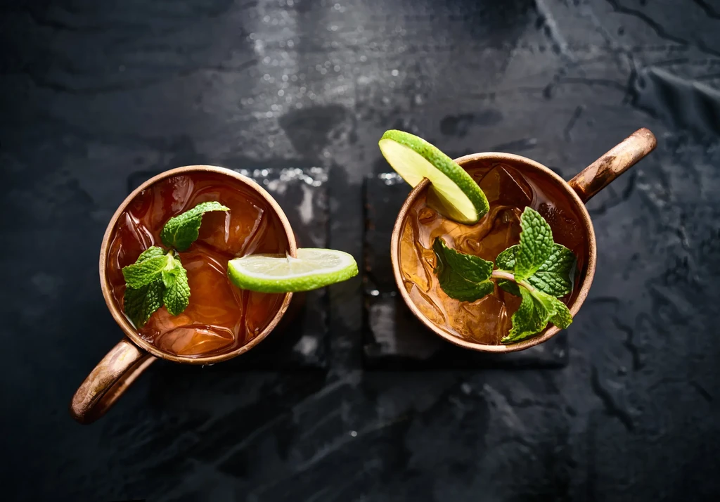 Two copper mugs filled with drinks, ice, mint, and lime.