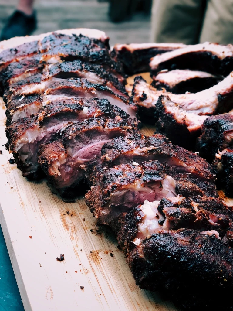 Sliced ribs on a wooden cutting board, with visible meat and char.