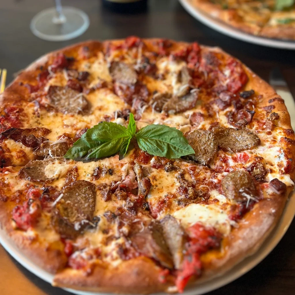 Freshly baked gourmet pizza with sausage, mozzarella, and basil.