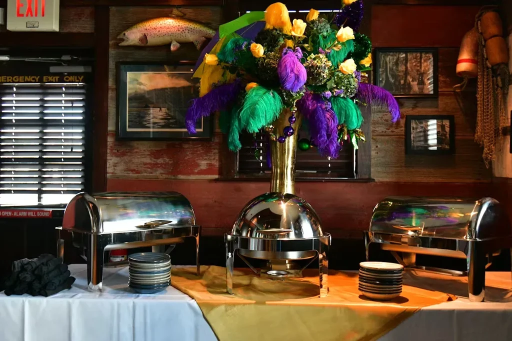 Mardi Gras buffet table with chafing dishes and feather centerpiece.