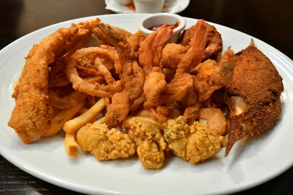 Fried seafood platter with fish, shrimp, crab, onion rings, and fries.