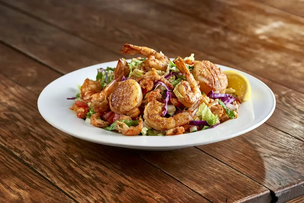 Colorful seafood salad with shrimp, scallops, greens, tomatoes, and lemon.