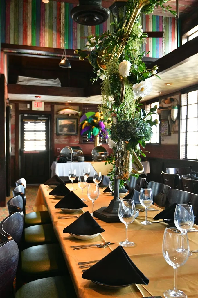 Long dining table with brass instruments, flowers, and golden tablecloth.