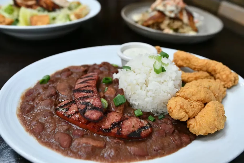 Plated red beans, rice, grilled sausage, fried shrimp, green onions.