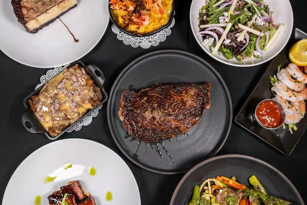 Top-down view of diverse, elegantly plated gourmet dishes on a dark surface.