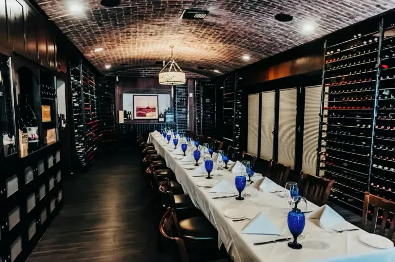 Wine cellar dining room with an arched brick ceiling and set table.