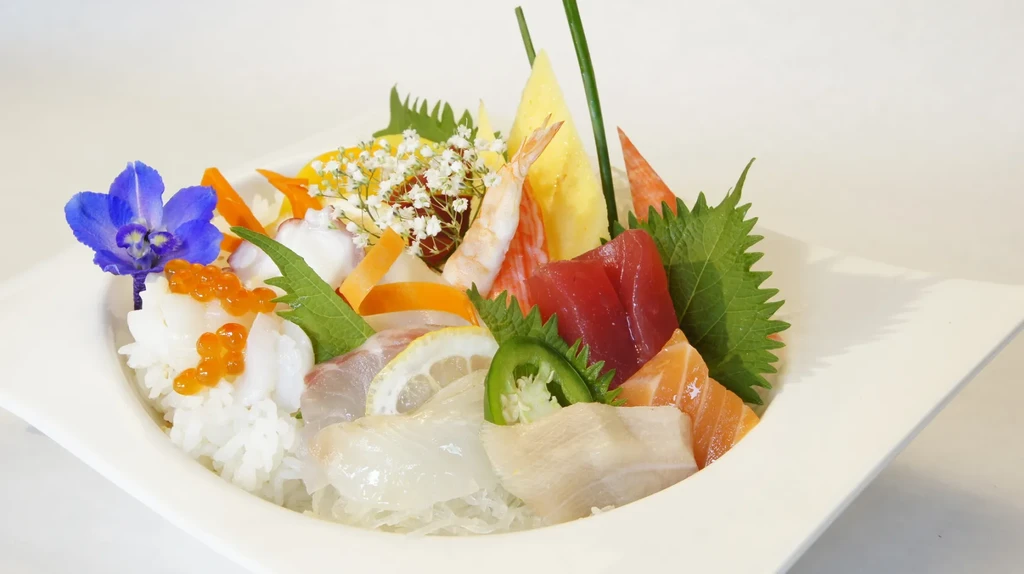 Vibrant chirashi bowl with various sashimi, rice, and colorful garnishes.
