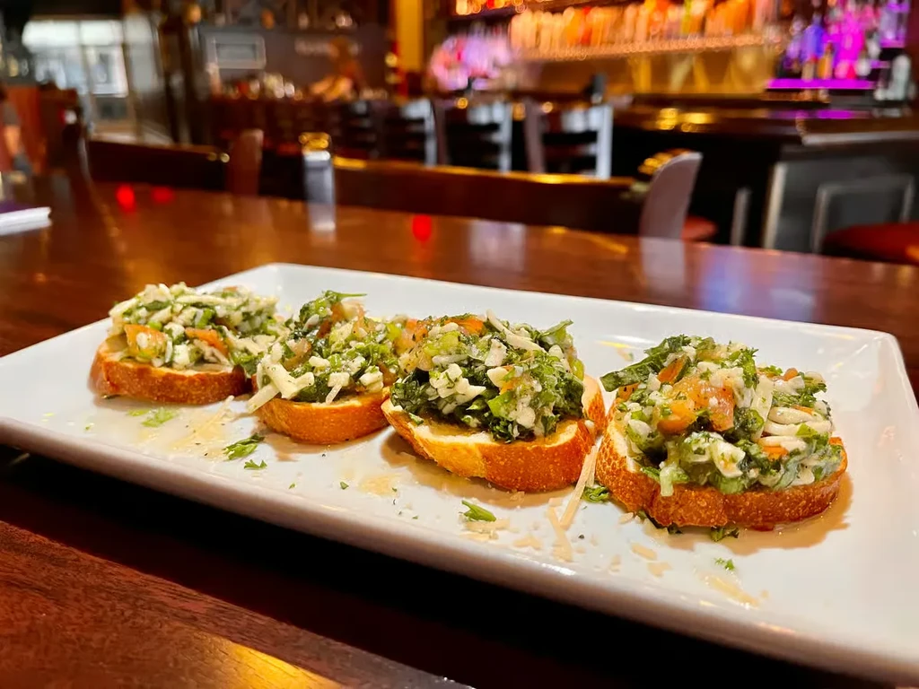 Close-up of four colorful bruschetta on a plate in a bar.