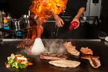 Chef creates a flaming onion volcano on a teppanyaki grill.
