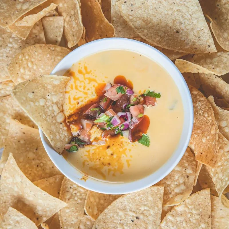 Queso dip with pico de gallo, chili oil, and tortilla chips.