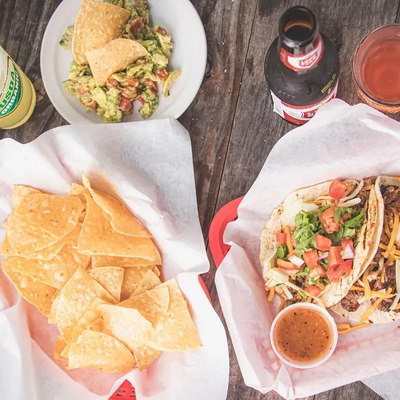 Overhead shot of a rustic table with Mexican dishes and drinks.