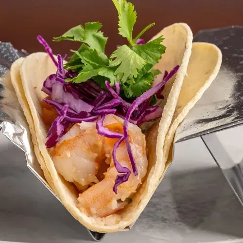 Close-up of a shrimp taco with purple cabbage and cilantro.