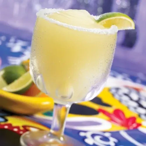 Frozen margarita with salted rim and lime in a stemmed glass.