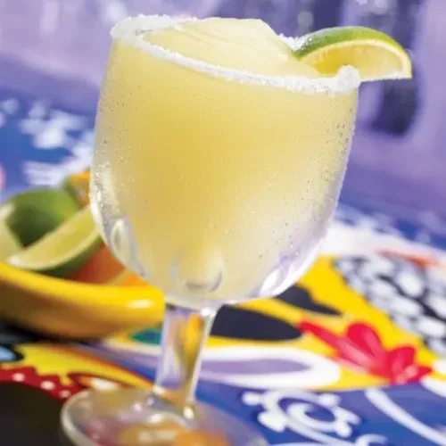 Close-up of a frosty pale yellow drink with a lime wedge.