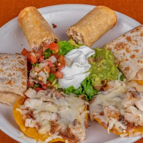 White plate with Mexican food, including flautas, quesadillas, tostadas.