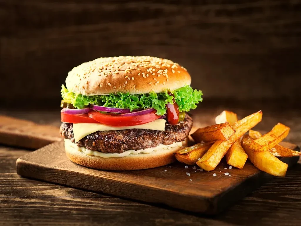 Hamburger and french fries on a wooden cutting board.