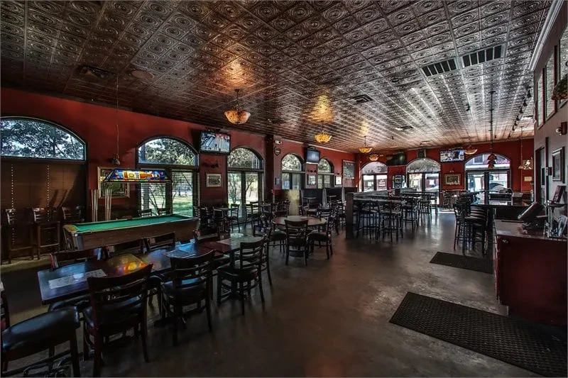 Empty bar with red walls, tin ceiling, and pool table.