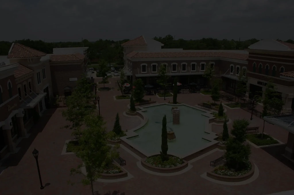 Aerial view of a brick plaza with a fountain and surrounding buildings.