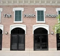 Brick building with "The Public House" sign and green shutters.