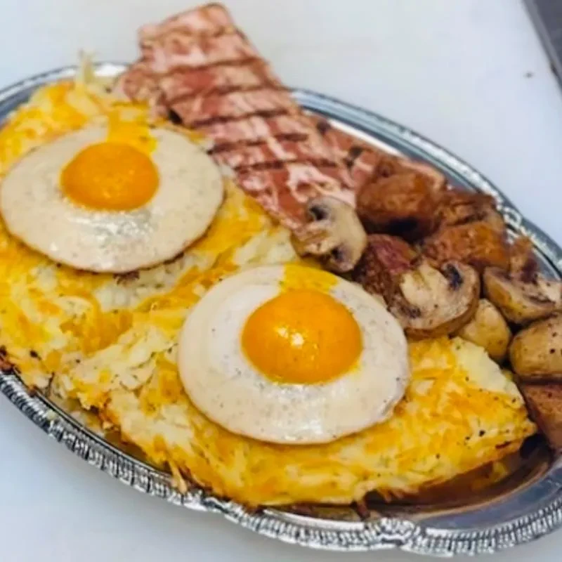 Full breakfast plate with hash browns, fried eggs, bacon, and mushrooms.