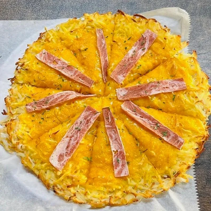 Hash brown crust pizza topped with cheese, bacon, and herbs.