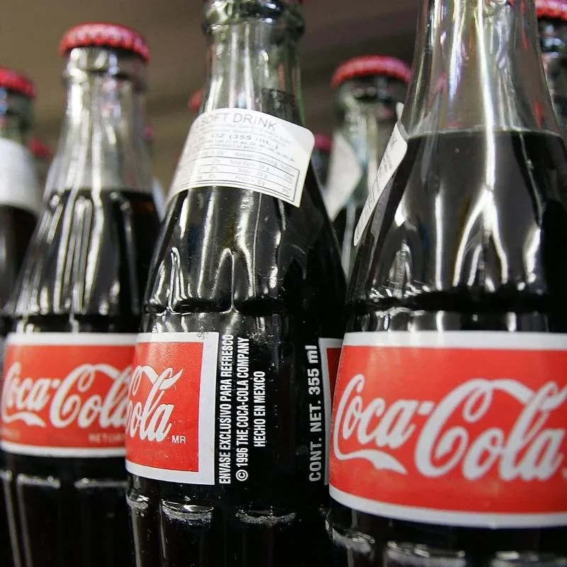 Several partially-filled glass Coca-Cola bottles with red and white labels.