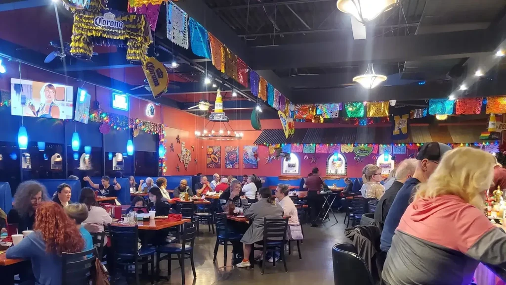 Interior of a lively Mexican restaurant with patrons, colorful decorations.