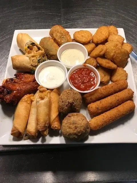A platter of various fried foods and three dipping sauces.