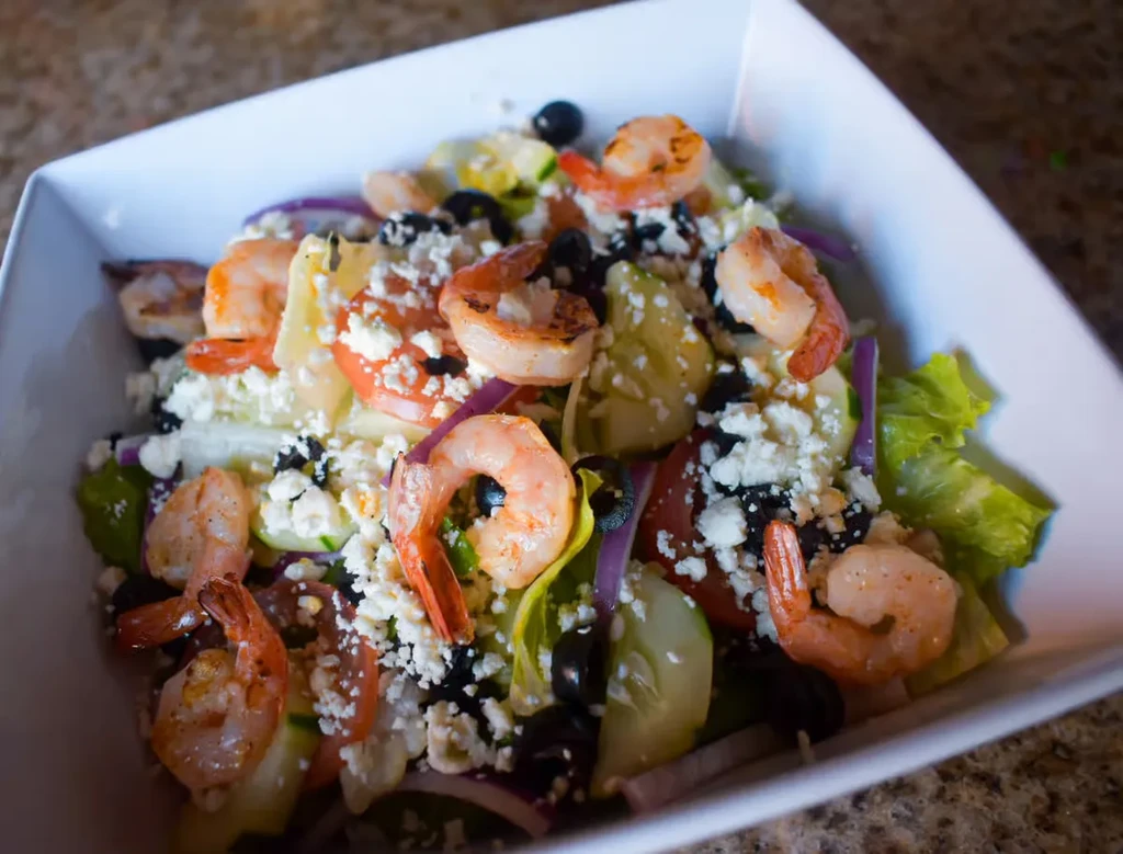 Grilled shrimp and feta salad in a white bowl.