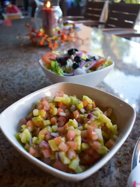 White bowls of diced vegetable salad and garden salad on table.