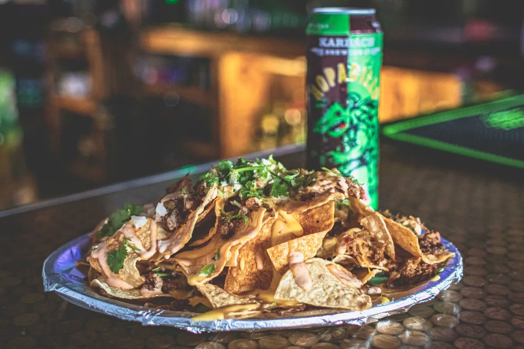 Plate of nachos with meat, onions, cilantro, and sauce.