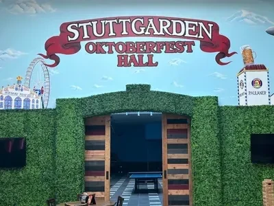 Stuttgarden Oktoberfest Hall entrance with themed murals and green hedge decor.