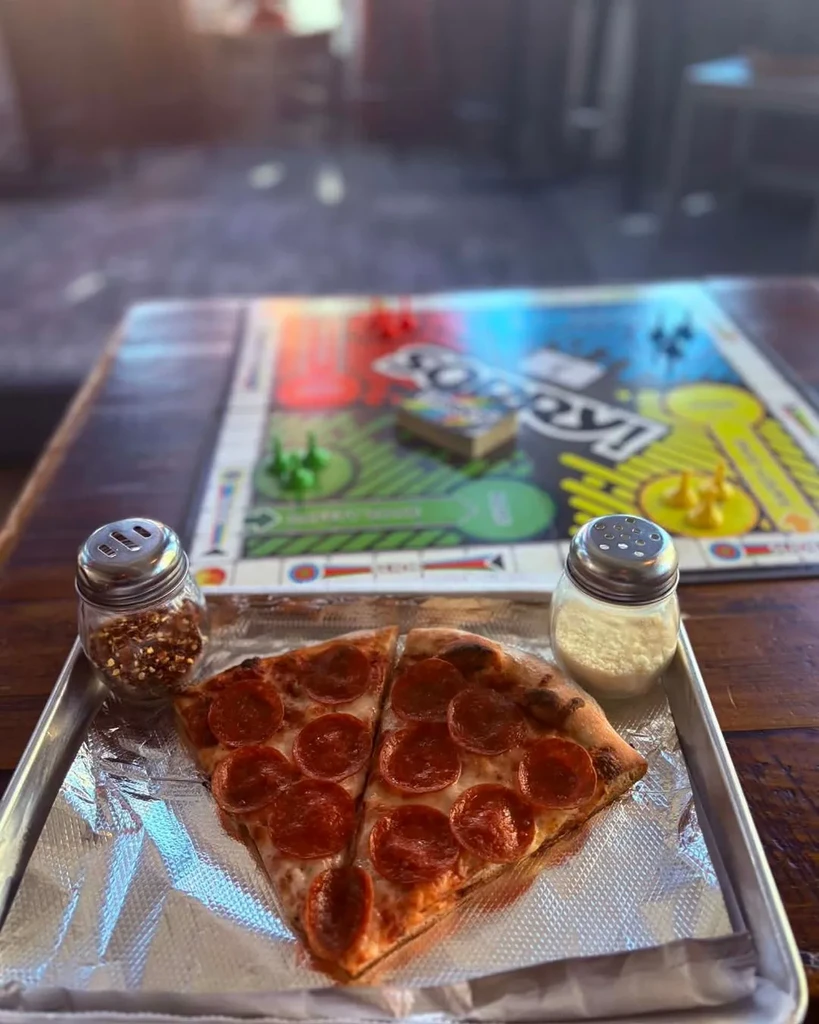 Two pepperoni pizza slices on a tray, shakers, and a 'Sorry!' game.