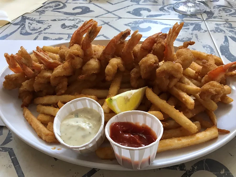 Plate of fried shrimp and fries with dipping sauces and lemon.