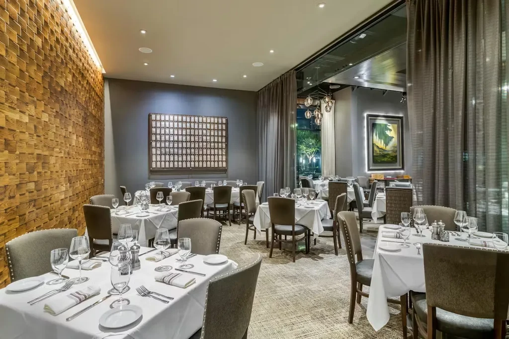 Elegant restaurant dining room with set tables, wooden blocks, and art.