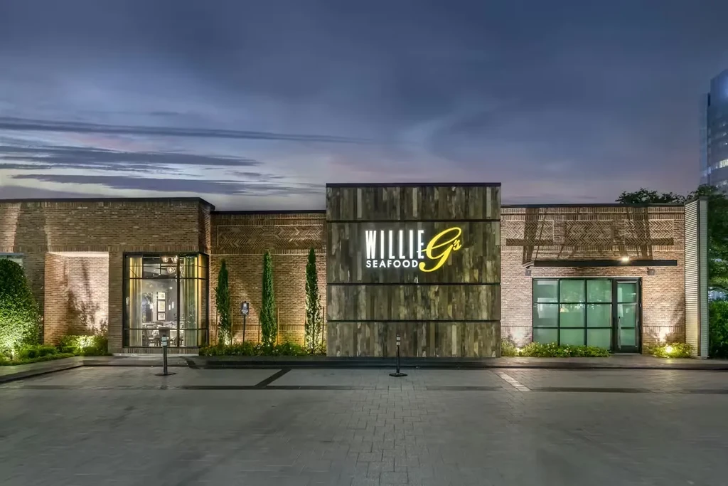 Illuminated modern brick and wood exterior of Willie G's Seafood.