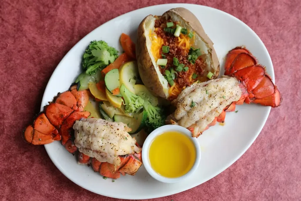 Overhead surf-and-turf plate with lobster, loaded potato, and vegetables.
