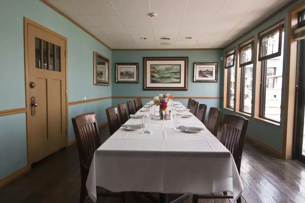 Elegant private dining room with a set table, artworks, and windows.