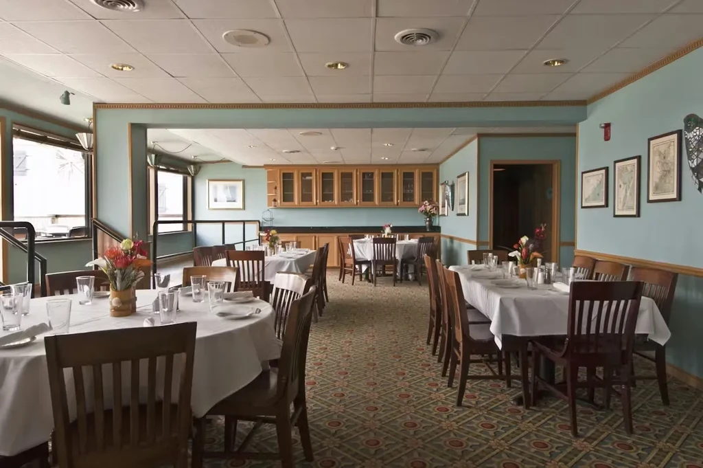 Empty restaurant dining room with set tables, chairs, and buffet.