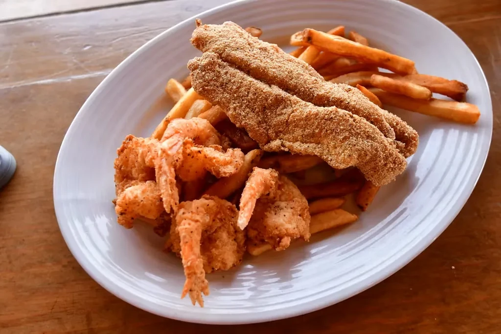 Overhead shot of fried fish, shrimp, and fries on an oval plate.
