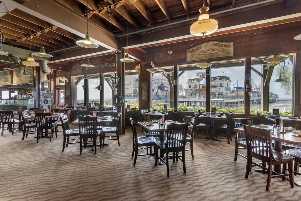 Empty nautical-themed restaurant with beach carpet and waterfront view.