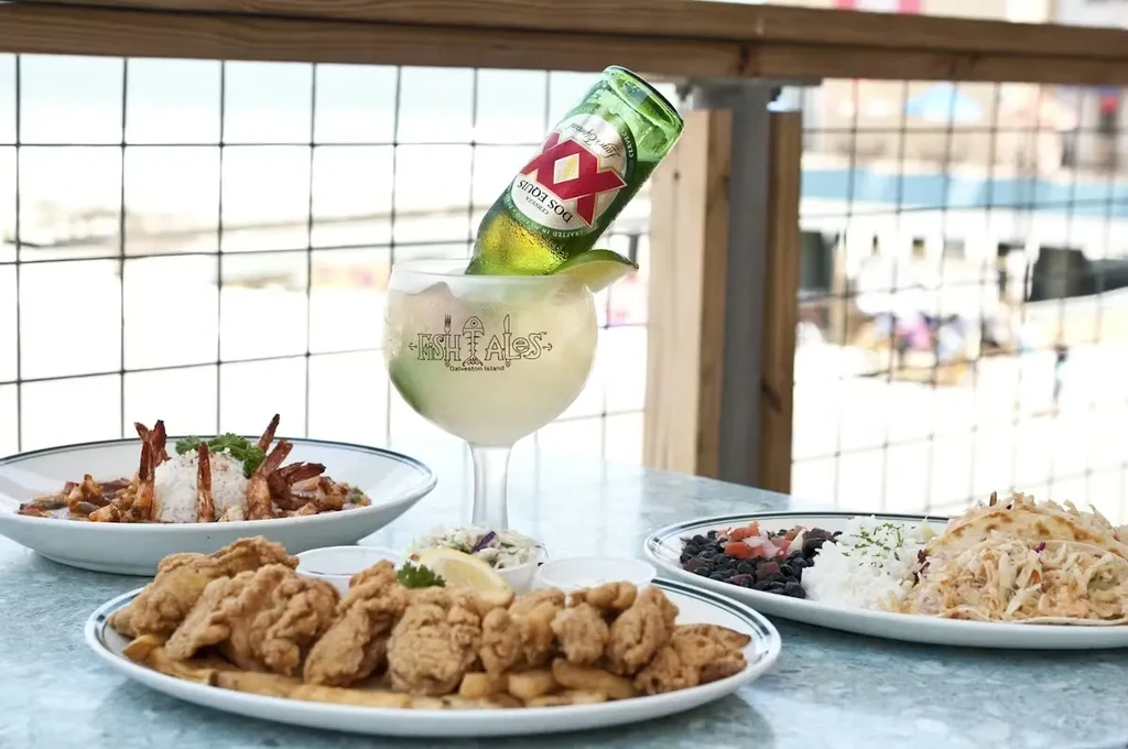Restaurant patio table with seafood, rice dishes, and a Dos Equis beer-margarita.
