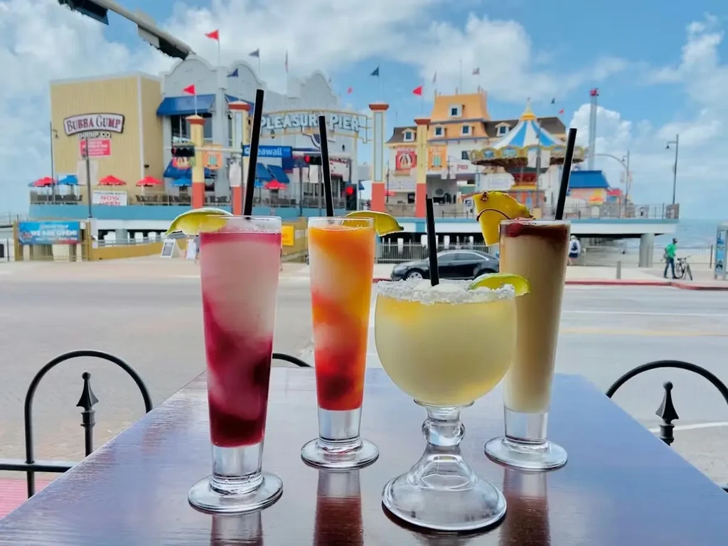 Four colorful mixed drinks overlooking Bubba Gump Shrimp Co. and Pleasure Pier.