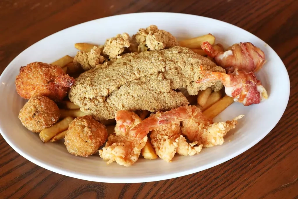 Fried seafood platter with fish, shrimp, hush puppies, and fries.