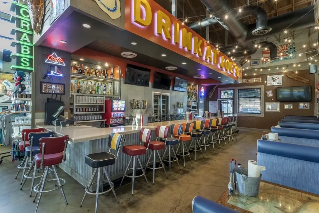 Colorful retro bar stools at a lively, industrial-nautical restaurant bar.