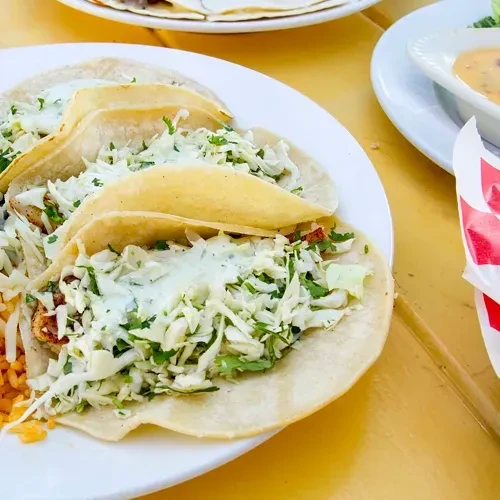 Three fish/chicken tacos with slaw, creamy sauce, and orange rice.