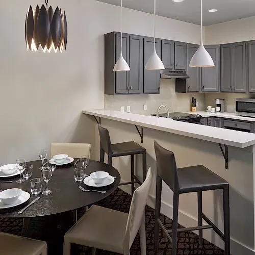 Modern dining area and kitchen with dark cabinets and bar.
