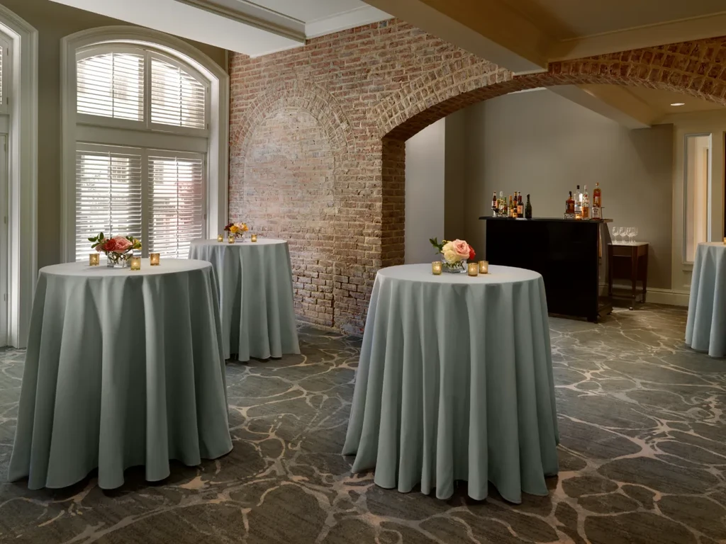 Three cocktail tables, flowers, candles, bar station, brick accent wall.